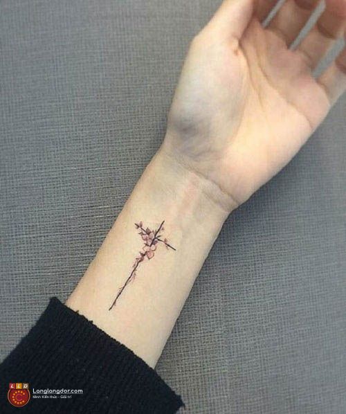 Tattoo nhỏ hình chữ thập kết hợp cùng hoa trên tay